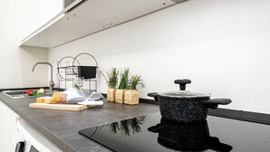 A kitchen with a black pot on the counter, a cutting board with bread, a sink, and a plant. - Italianway Comfort - Cicco Simonetta 16/a (Milan)