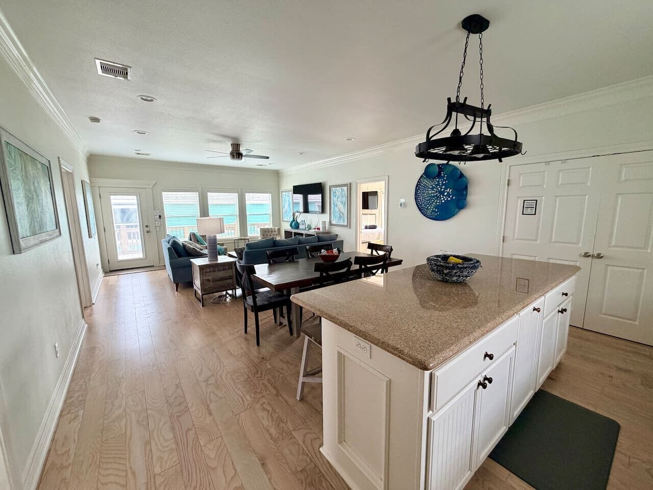 A spacious kitchen with a central island, a dining area with a sofa and chairs, and a large window providing natural light.