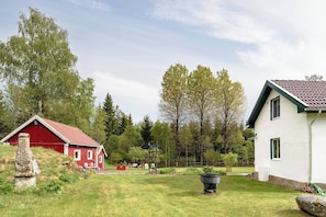 A red barn and a white house with a sloped roof, surrounded by a grassy yard and trees. - 3BR In Kosta - Fire pit, gathering room, Lake &Pub (Källeskruv)