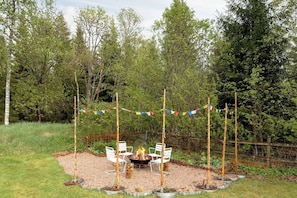 An outdoor seating area with a fire pit, surrounded by a wooden fence and trees. - 3BR In Kosta - Fire pit, gathering room, Lake &Pub (Källeskruv)