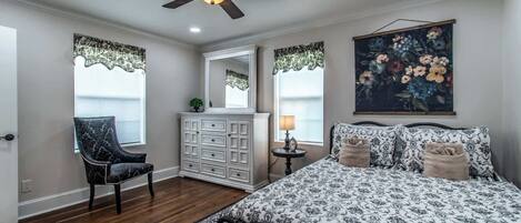 Un dormitorio con cama, cómoda, silla y ventilador de techo.