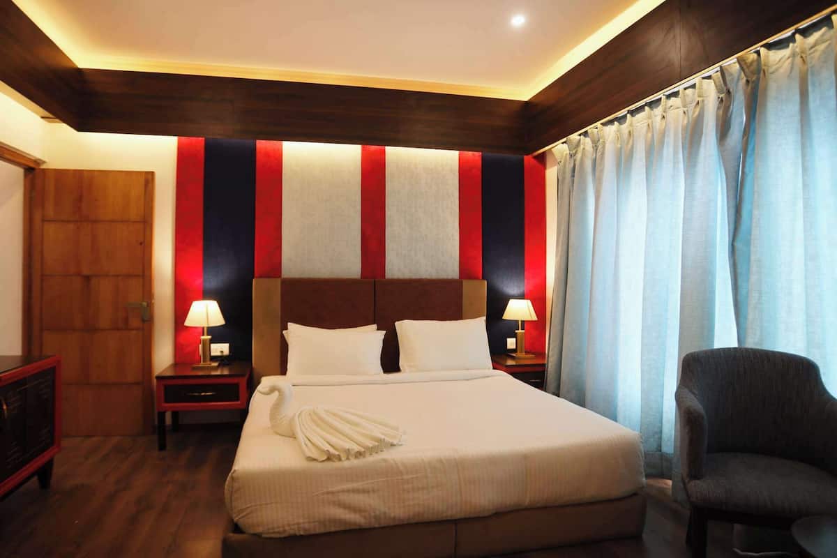A hotel room with a large bed, two bedside tables with lamps, a wooden headboard, and a chair.