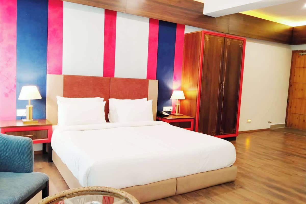 A hotel room with a bed, bedside tables, a wardrobe, and a chair.