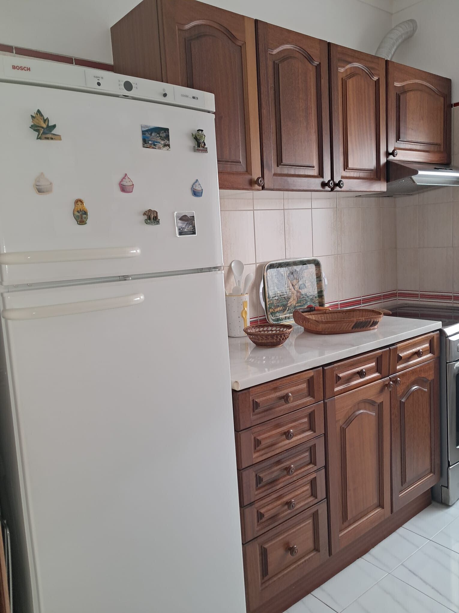 A kitchen with wooden cabinets, a white refrigerator, and a tiled backsplash.