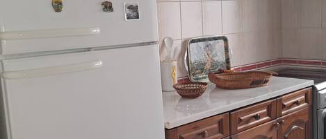 A kitchen with wooden cabinets, a white refrigerator, and a tiled backsplash.