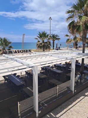 Ein Restaurant direkt am Strand mit Außenbereich, Palmen und Meerblick.