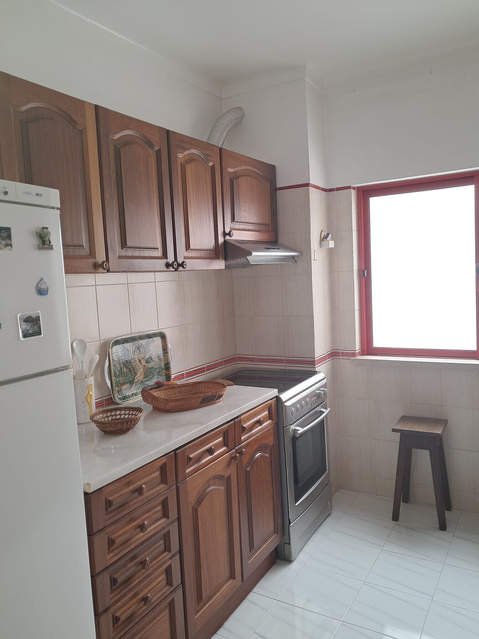 A kitchen with wooden cabinets, a stainless steel oven, and a window.