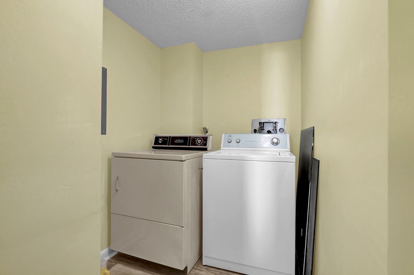 Une buanderie équipée d’un lave-linge et d’un sèche-linge, d’un petit meuble de rangement et d’un téléviseur noir.