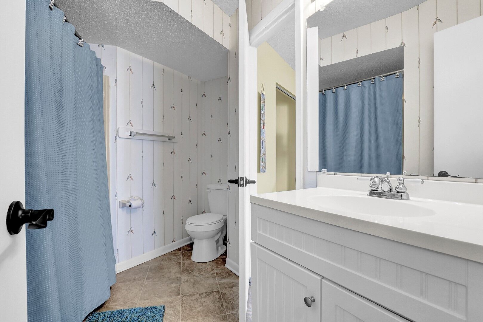 Un baño con inodoro, lavamanos y cortina de ducha.