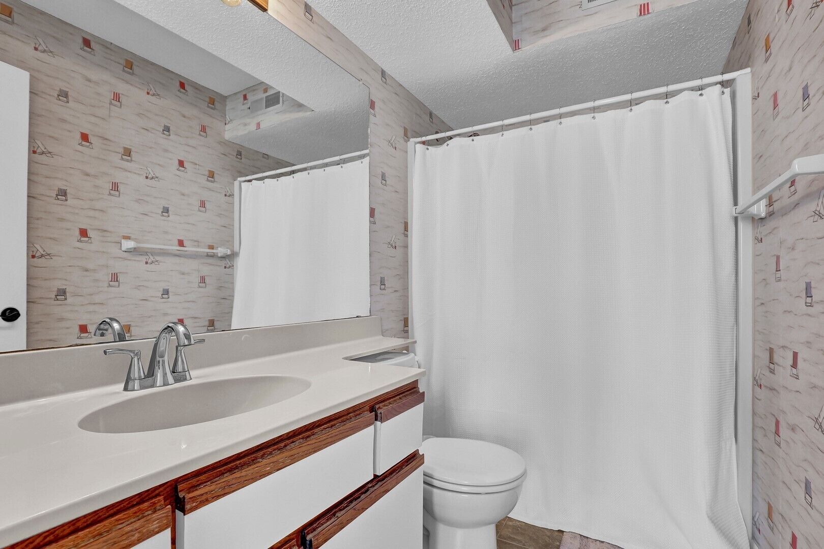 A bathroom with a white sink, mirror, and toilet, and a shower curtain.