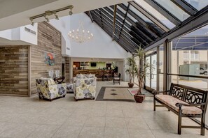 Eine geräumige Lobby mit hoher Decke, einem Empfangsbereich und einer Sitzecke mit gemusterten Sofas.