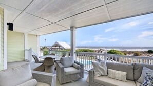 Un espace extérieur aménagé avec des meubles en osier, une table et une vue sur la plage.