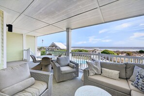 A covered outdoor seating area with wicker furniture, a table, and a view of the beach. - Oceanfront 3BR Condo with Panoramic Beach Views | Isle of Palms (Isle of Palms)