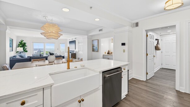 Une cuisine moderne avec des meubles blancs, un lave-vaisselle intégré et un grand îlot central.
