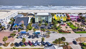 Un hôtel situé sur la côte, doté d’un parking, offrant une vue sur la plage et présentant un mélange d’architecture moderne et traditionnelle.