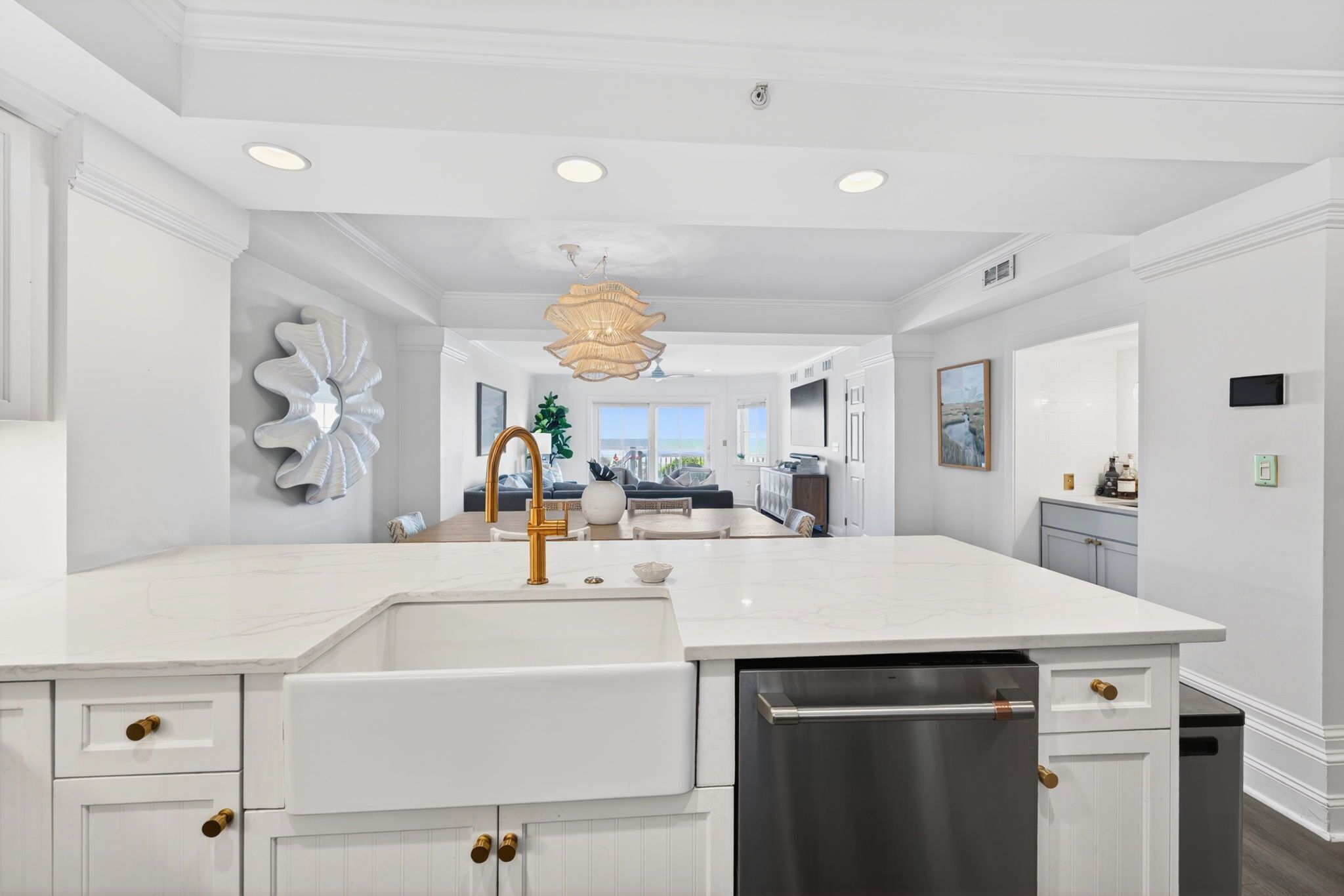 A modern kitchen with white cabinetry, a stainless steel dishwasher, and a central island with a sink.