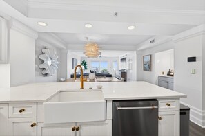 A modern kitchen with white cabinetry, a stainless steel dishwasher, and a central island with a sink. - Oceanfront 3BR Condo with Panoramic Beach Views | Isle of Palms (Isle of Palms)