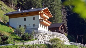 Un edificio de estilo chalé con base de piedra, estructura superior de madera y un balcón con jardineras.