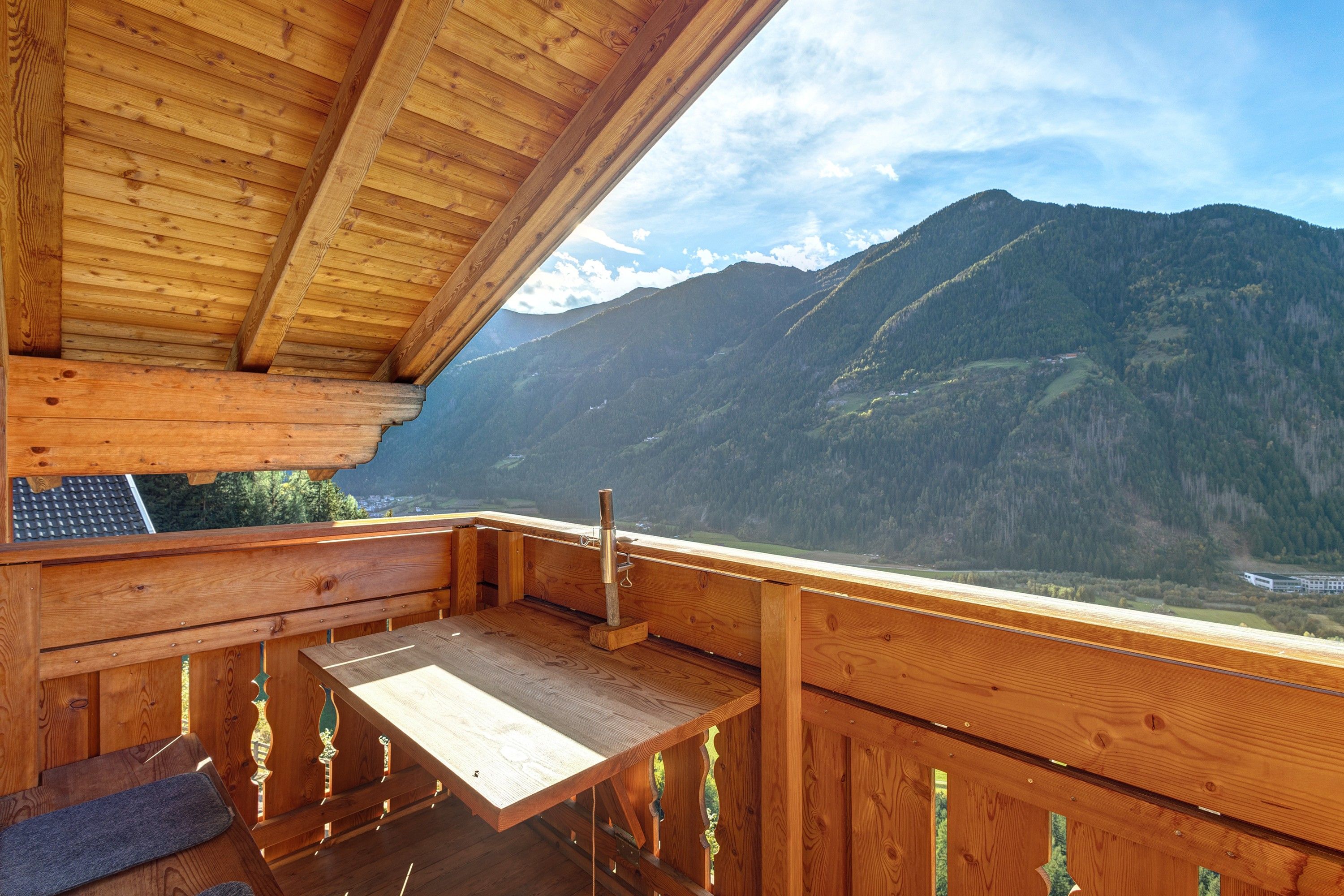 Une terrasse en bois avec un banc et une table, offrant une vue sur un paysage montagneux.