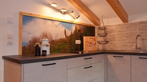 Una cocina moderna con techo de madera, un ventanal con un cuadro y un lavamanos con un grifo moderno.