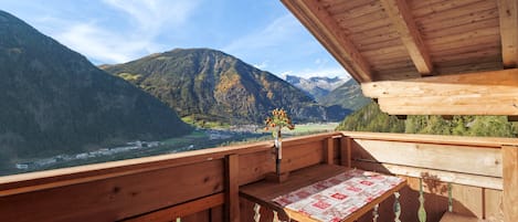 A wooden balcony with a view of a valley and mountains.