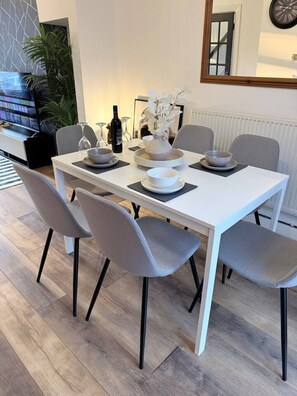 Ein Essbereich mit einem weißen Tisch, grauen Stühlen und moderner Einrichtung.