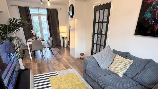 Ein Wohnzimmer mit einer Couch, einem Fernseher, einem Teppich und einem Essbereich.