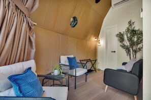 Ein Zelt-ähnliches Zimmer mit einer Couch, Stühlen, einem kleinen Tisch mit einer Pflanze und einer Tür.