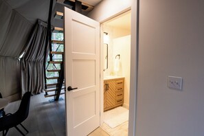 Ein Zimmer mit einer weißen Tür, einem Holzschrank, einem weißen Teppich und einer Treppe mit Geländer.