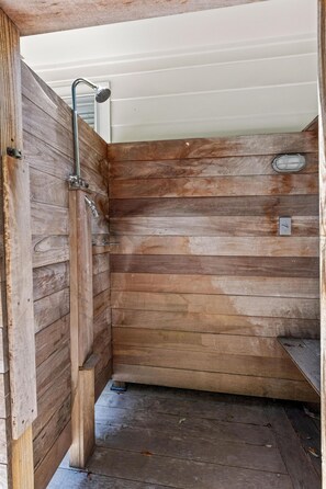 L’intérieur d’une cabane en bois, avec une douche, des murs en bois et un banc.