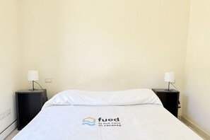 Une chambre d’hôtel avec un lit, deux tables de chevet et une lampe sur chaque table.