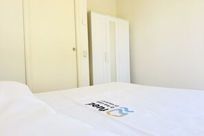 Quarto de hotel com uma cama, um guarda-roupa e uma porta.