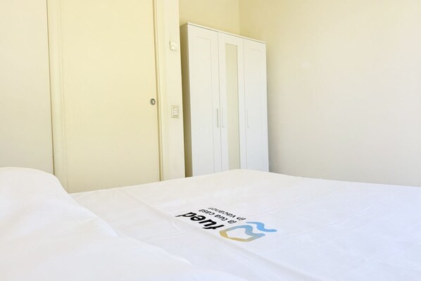 A hotel room with a bed, a wardrobe, and a door.