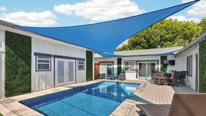 A swimming pool with a deck, outdoor seating, and a shaded area. - Completely re-done 4 bedroom pet-friendly home. Great location. (St. Simons Island)
