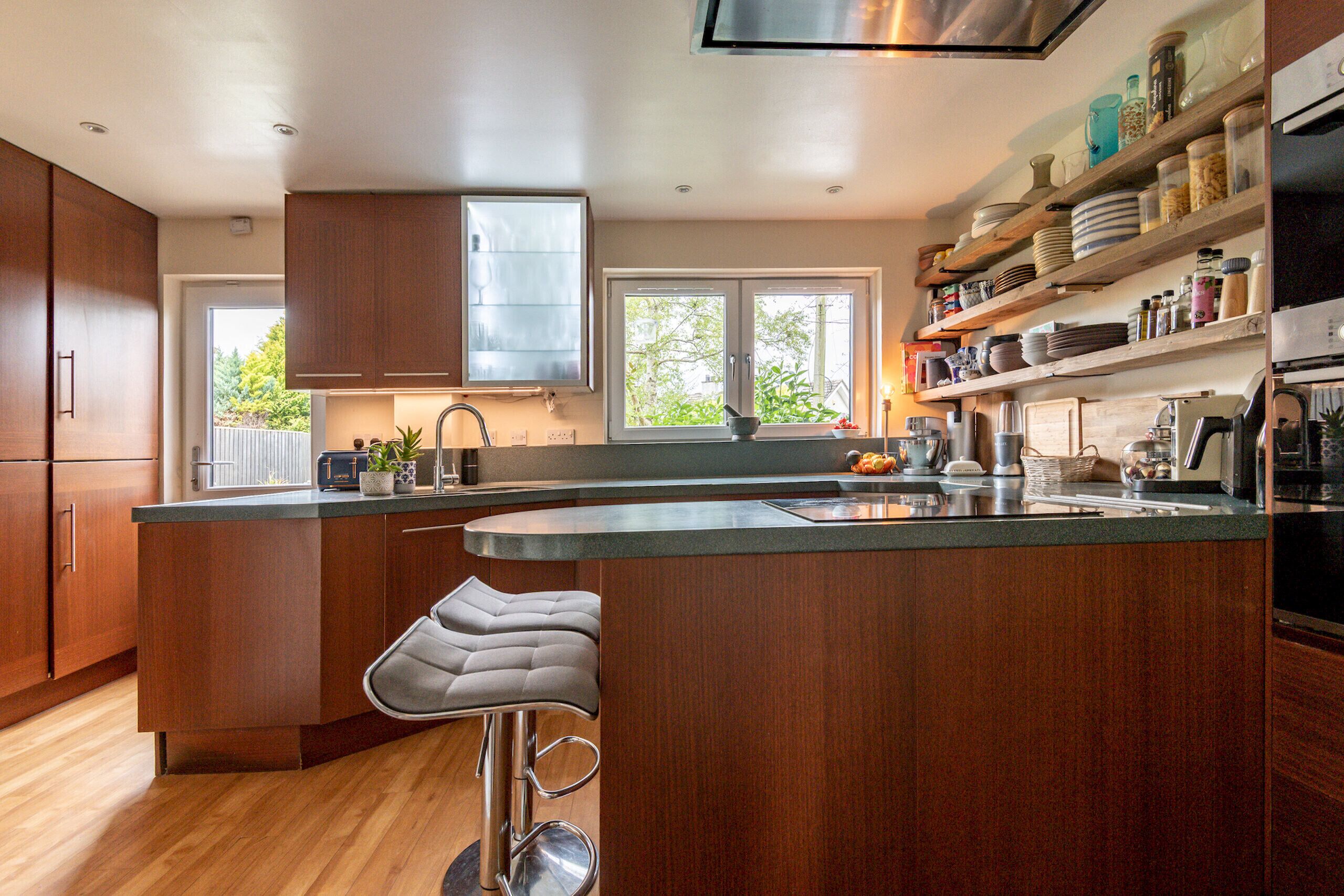 Une cuisine moderne avec des meubles en bois, un grand îlot central doté de tabourets, une fenêtre offrant une belle vue et divers appareils de cuisine.