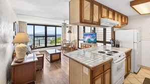 Una cocina moderna con armarios de madera, una isla central, horno integrado y un amplio ventanal con vistas.