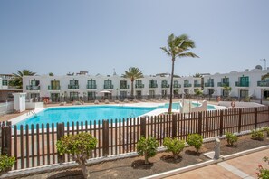 Un hotel con piscina, varios balcones y una cerca de madera.