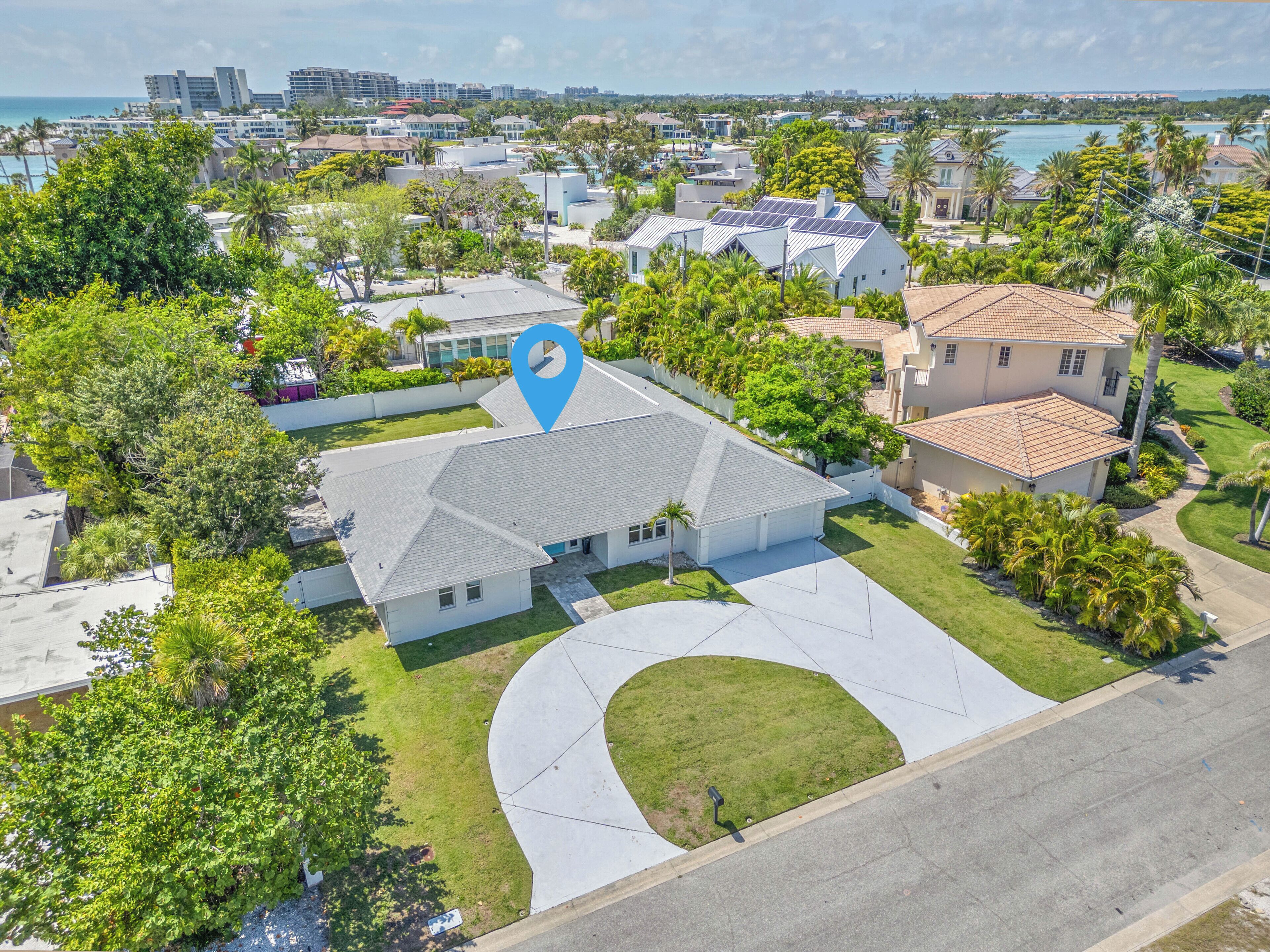 An aerial view of a residential area with houses, a large blue location pin, and a body of water in the background.