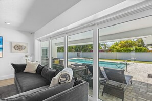 Ein modernes Wohnzimmer mit einem großen Glasfenster, das zum Poolbereich führt.