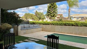 A patio with a glass table and chairs, a pool, and a view of the surrounding landscape. - villa Bouznika Bay by Saloua (Cherrat)