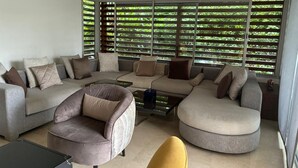 A modern living room with a sectional sofa, a round coffee table, and a yellow armchair. - villa Bouznika Bay by Saloua (Cherrat)