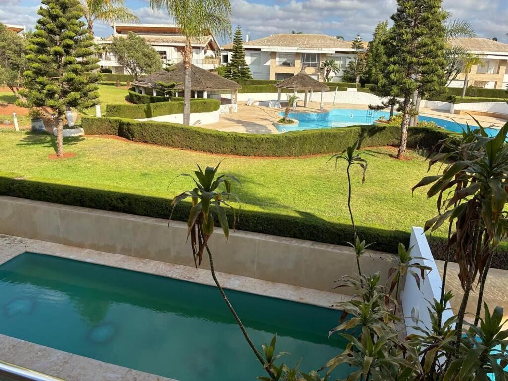 Zona residencial con piscina, césped cuidado y diversas especies de árboles.