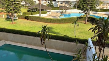 Zona residencial con piscina, césped cuidado y diversas especies de árboles.