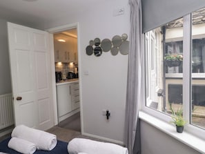Una habitación con cama, ventana con vistas, espejo en la pared y puerta que da a una cocina.