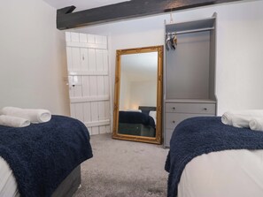 Un dormitorio con dos camas, un armario, un espejo y una puerta.