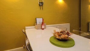 A dining table with a decorative centerpiece, a bottle of wine, and a framed picture on the wall.