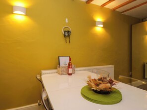 A dining table with a decorative centerpiece, a bottle of wine, and a framed picture on the wall. - Courtyard Cottage (Grange-over-Sands)