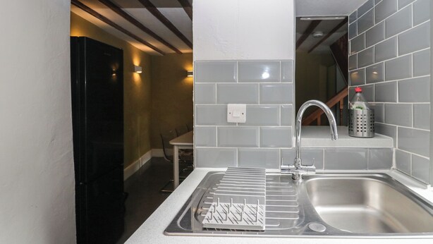 A modern kitchen with a stainless steel sink, a drying rack, and a bottle of hand soap on the countertop.