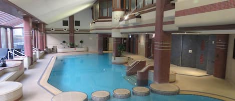 Piscina interior con varios niveles, zonas de estar y sección de spa.