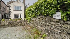A stone wall with a sign indicating a courtyard cottage.